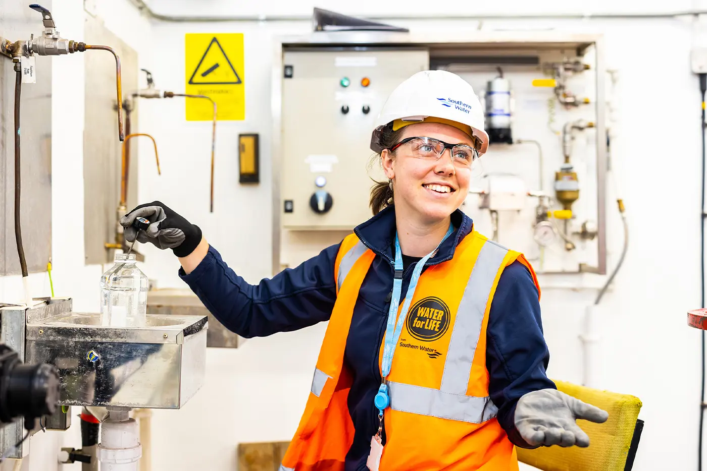 A Southern Water engineer smiles and tests a water sample in a water treatment works