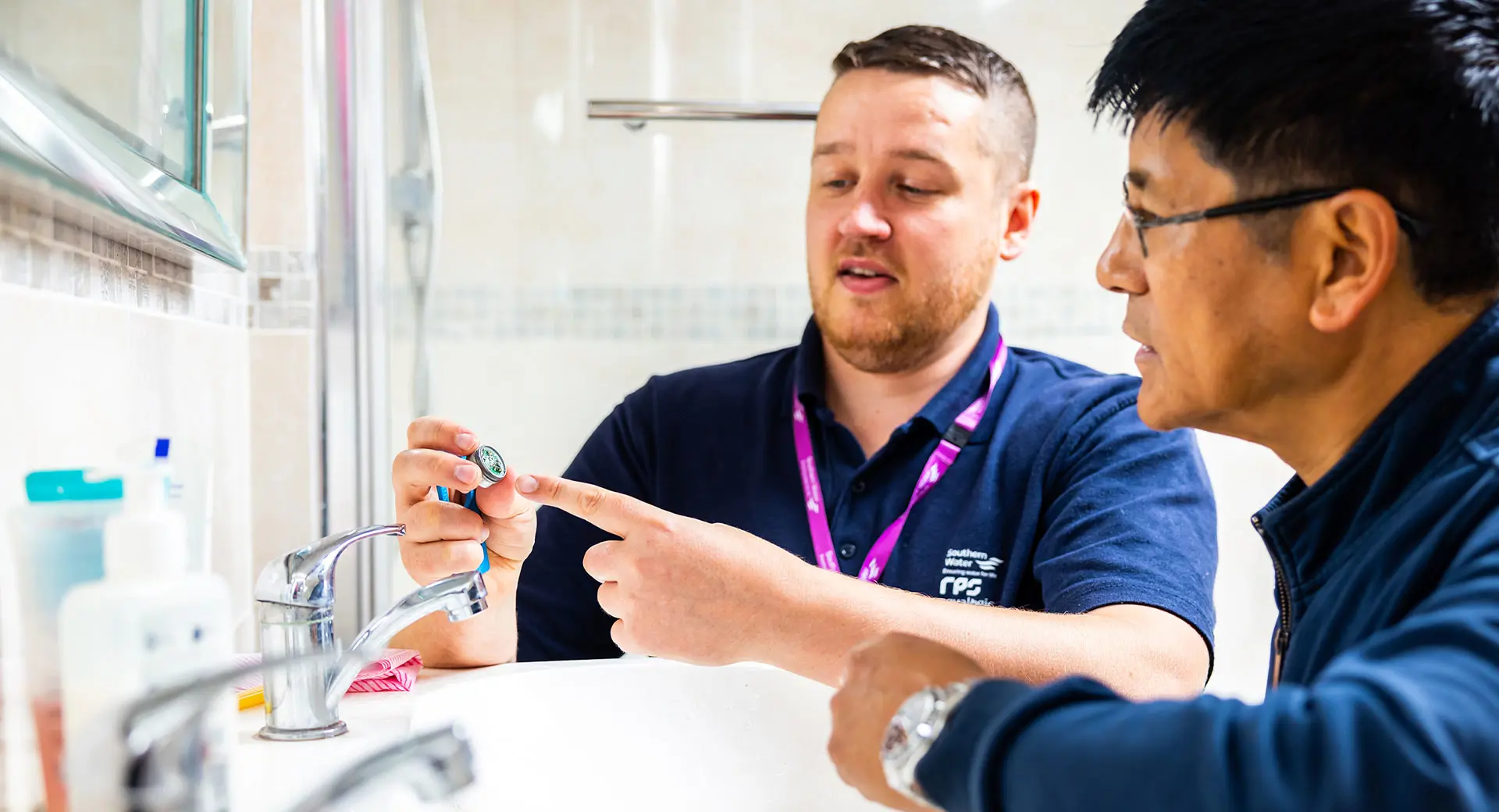 A Southern Water employee showing a tap aerator to a customer in a bathroom