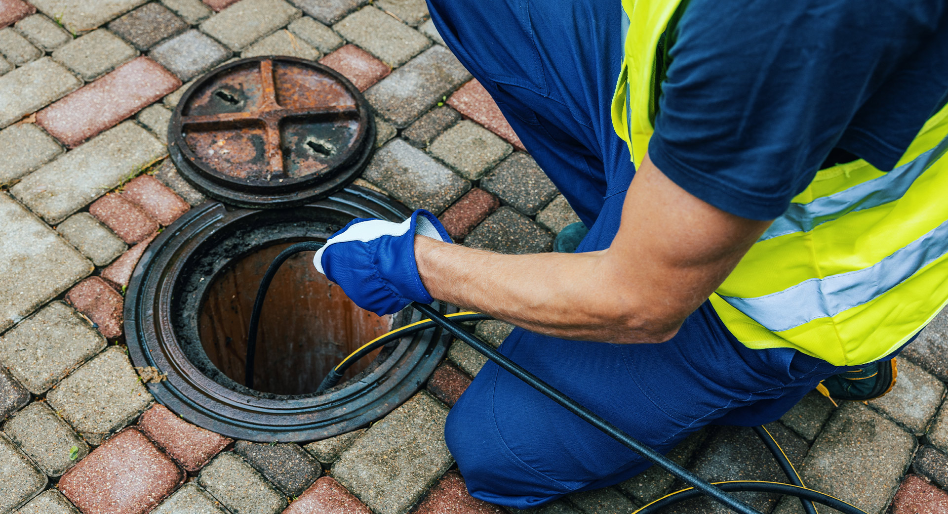 A Southern Water worker putting pipes down a drain
                        