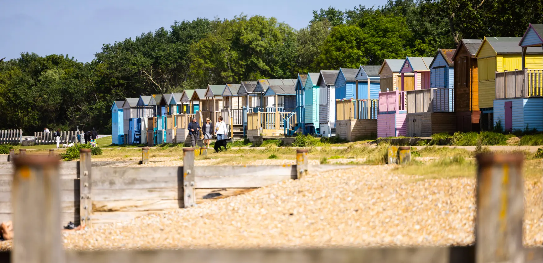 A closeup of beach huts on a beach with groynes